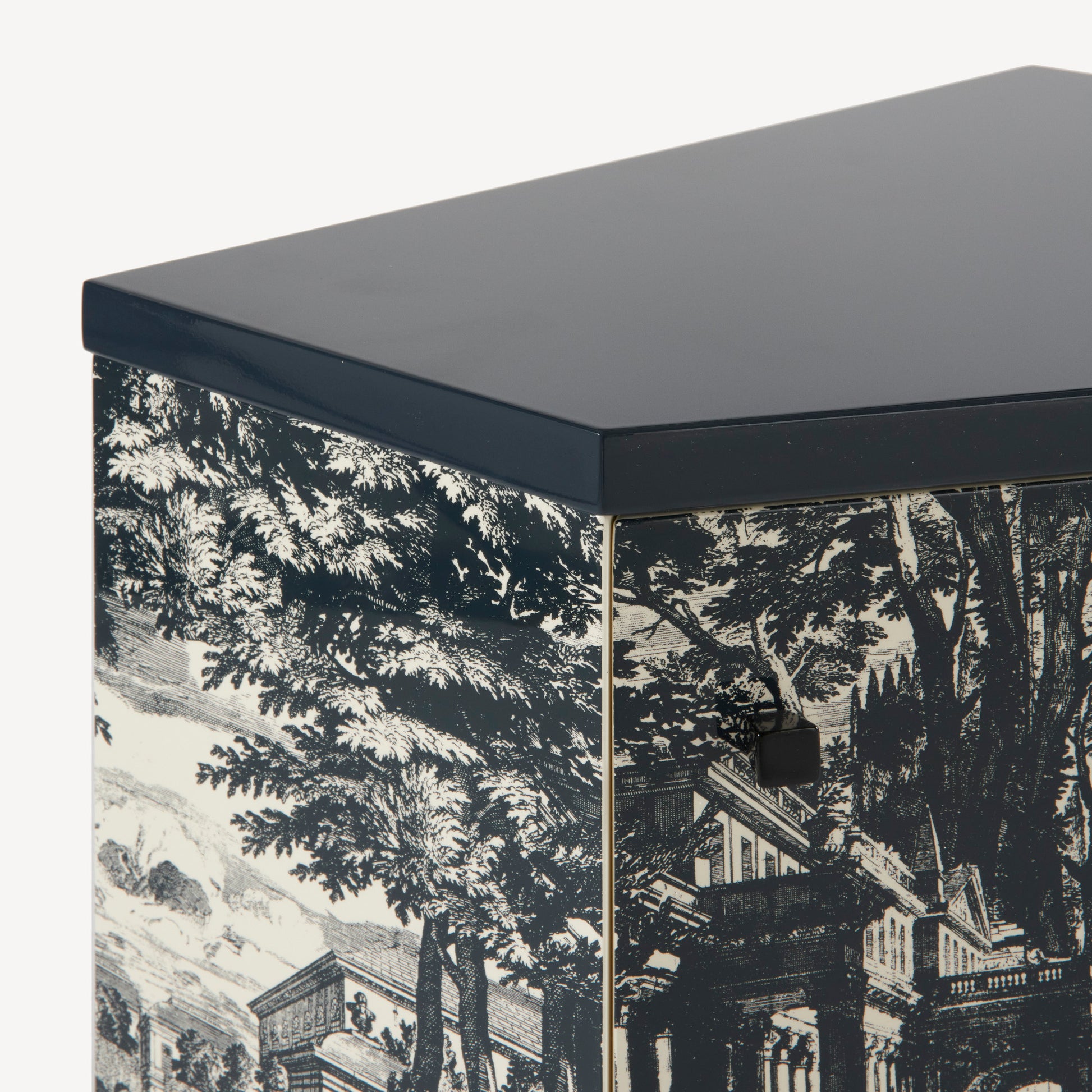 Close-up of nightstand with dark blue top and black-and-white toile pattern sides